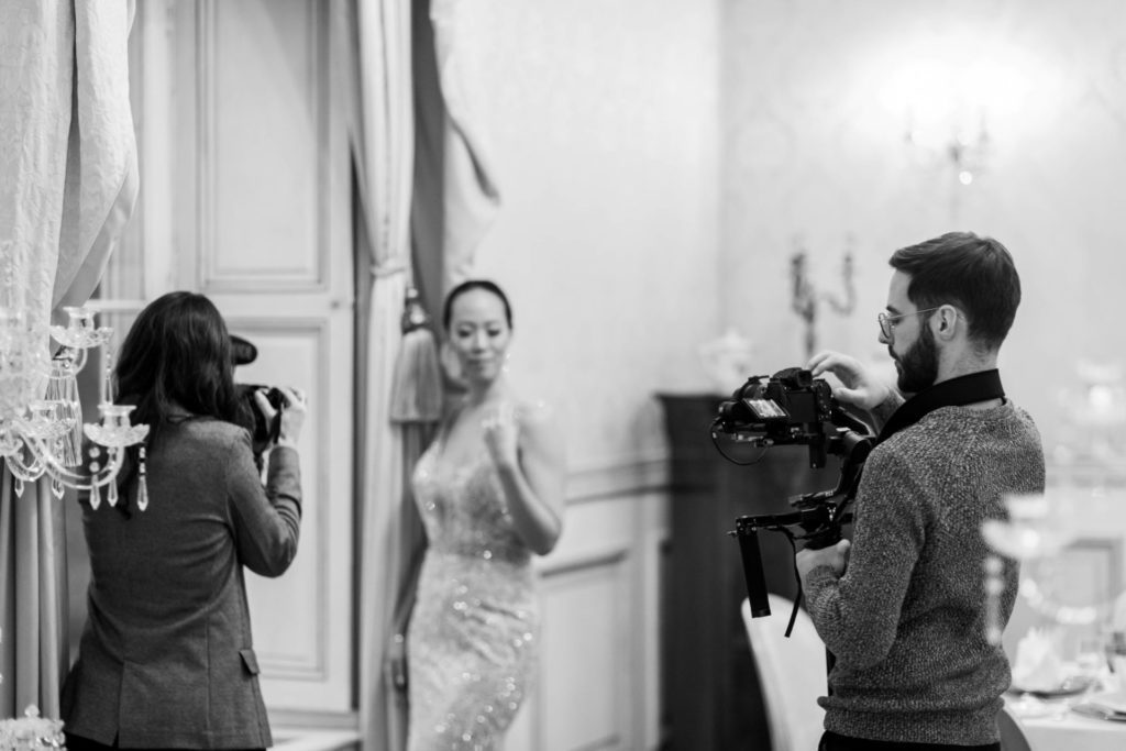 Two videographers recording a video of a woman in an evening dress